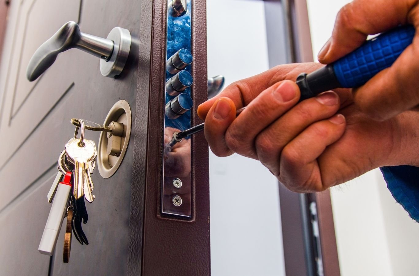 Skilled locksmith inspecting door hardware and rekeying cylinder with specialized tools. Locksmith near me.